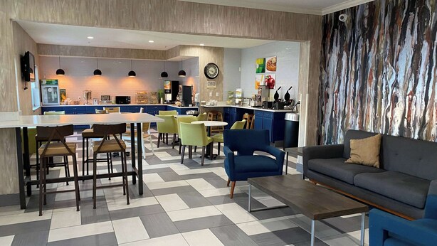 A modern interior with a dining area, kitchen, and seating space. - Wingate by Wyndham Uniontown (Uniontown)