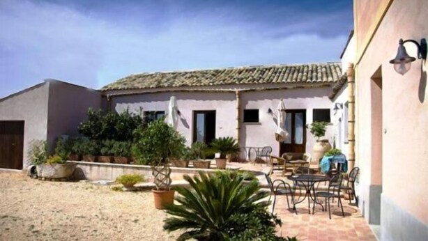 A courtyard with a patio area, outdoor furniture, and potted plants. - Agriturismo Baglio Donna Santa (Paceco)