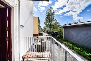A narrow alleyway with a metal fence, a red-tiled bench, and a building with a 'Reception' sign. - Guesthouse Andrea (Reykjavik)