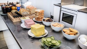 Une table de buffet proposant divers aliments, notamment du pain, du fromage, du jambon et des légumes.