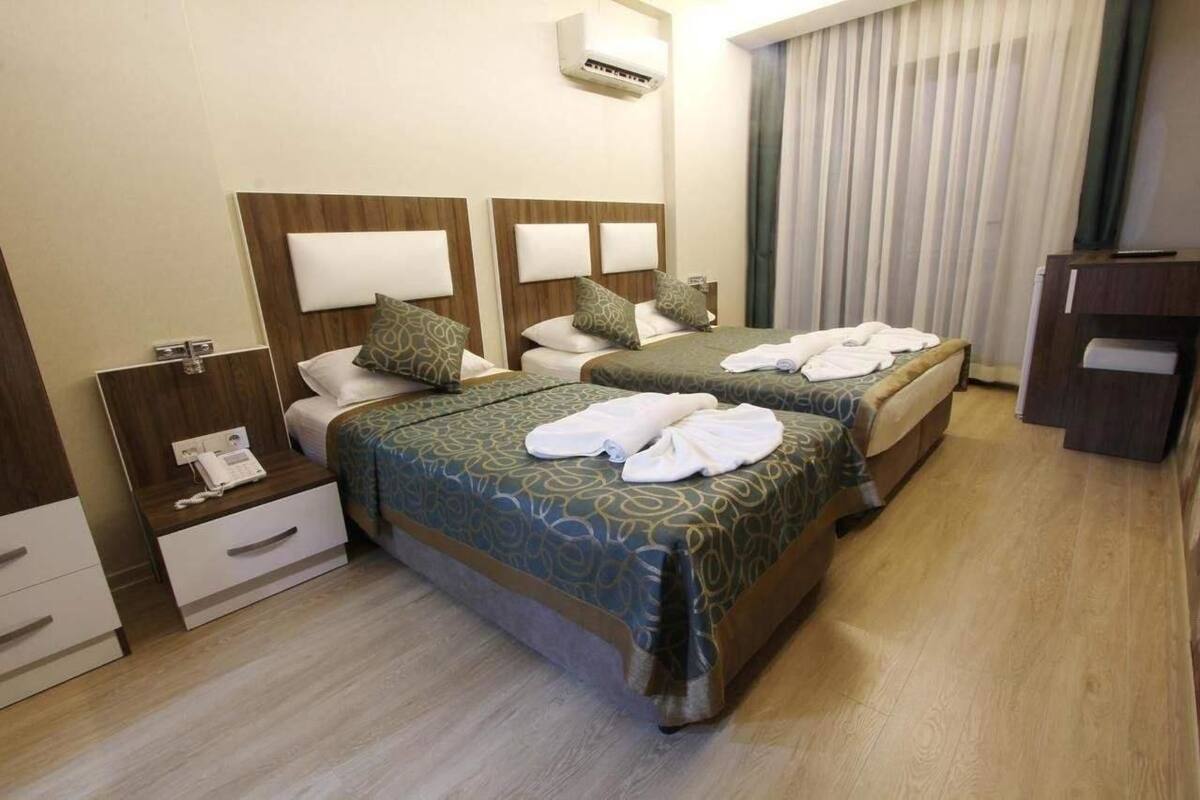 Une chambre d’hôtel avec deux lits, une table de chevet avec un téléphone et un meuble pour la télévision.