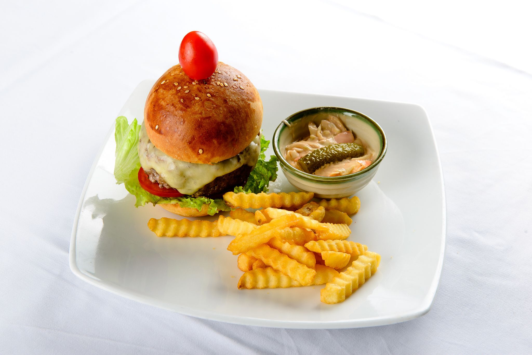 Ein Teller mit einem Burger, Pommes und einer kleinen Soße.
