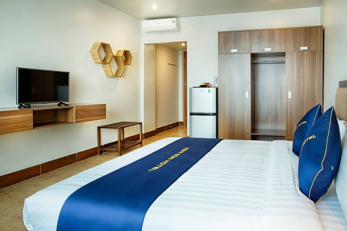 Ett hotellrum med en säng, en tv, en garderob och ett kylskåp.