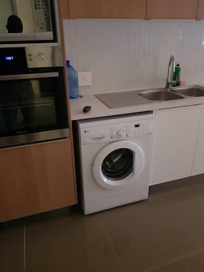 Una cocina equipada con microondas, horno, lavadora y lavaplatos.