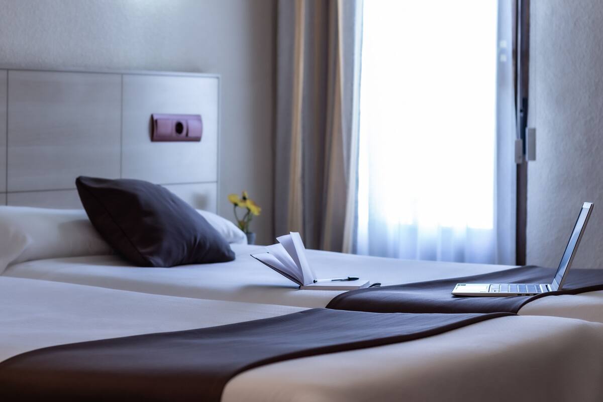 Quarto de hotel com cama, um laptop e um livro sobre a cama.