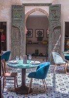 Un comedor con una mesa redonda, sillas azules y un suelo estampado.