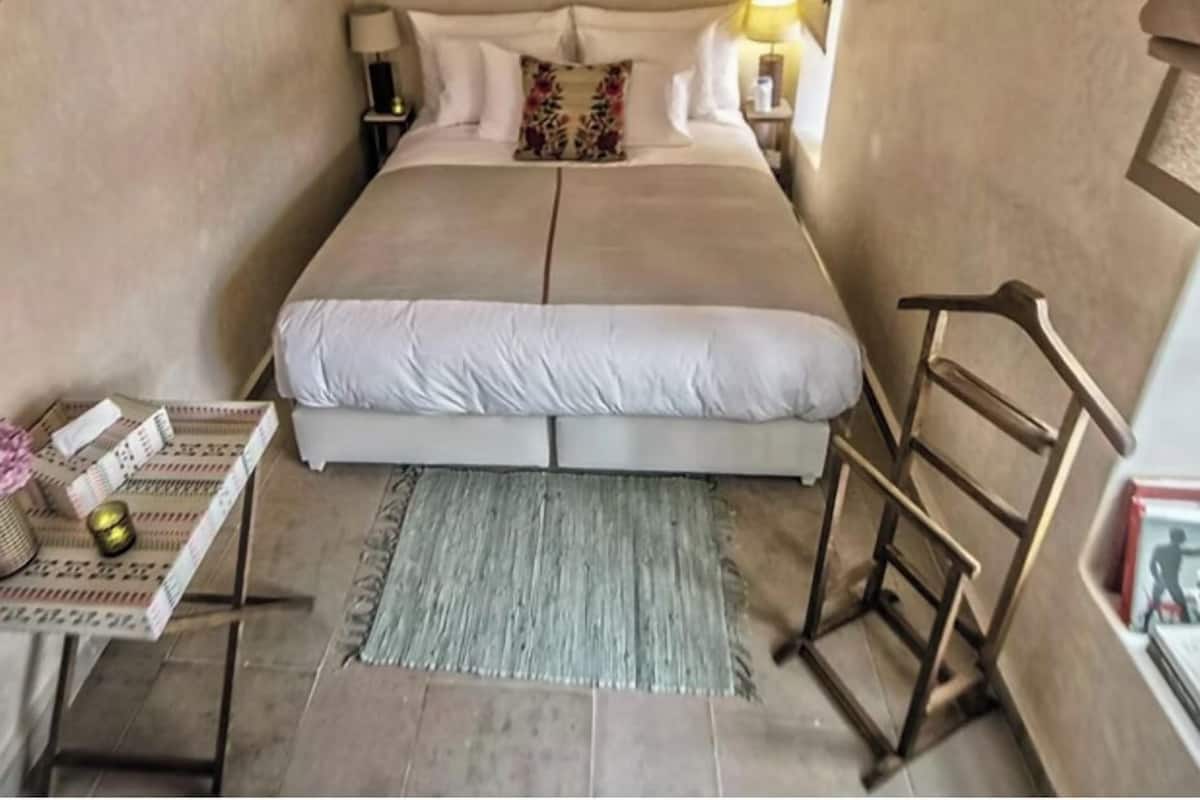 A bedroom with a large bed, bedside tables, a nightstand, a chair, and a rug.