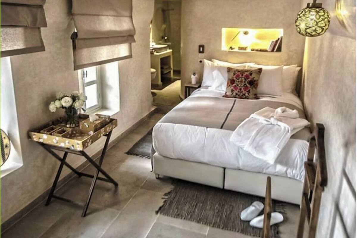 A bedroom with a large bed, a bedside table with a lamp, and a view into the bathroom.