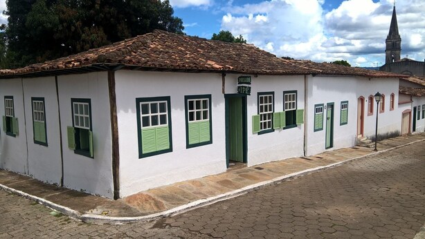 A white building with green shutters and a tiled roof. - Pousada do Ipê (Goiás)