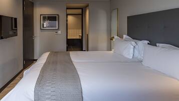 A hotel room with a large bed, a bedside table, a mirror, and a door leading to a bathroom.
