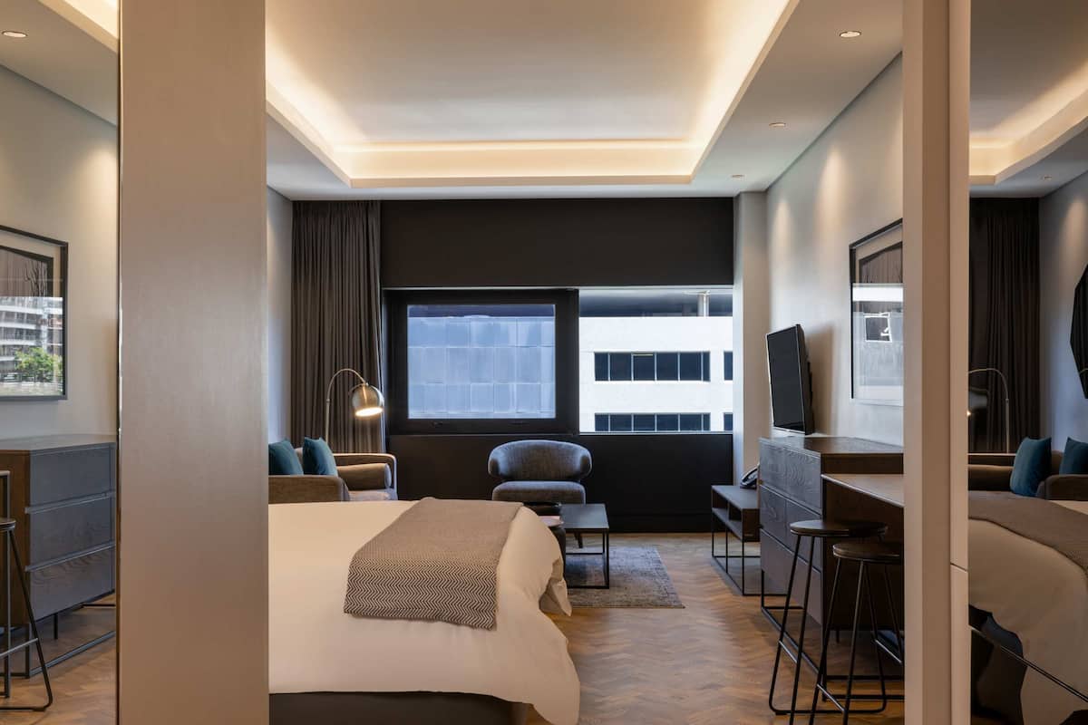 Une chambre d’hôtel moderne équipée d’un grand lit, d’un bureau, d’une chaise et d’un téléviseur.