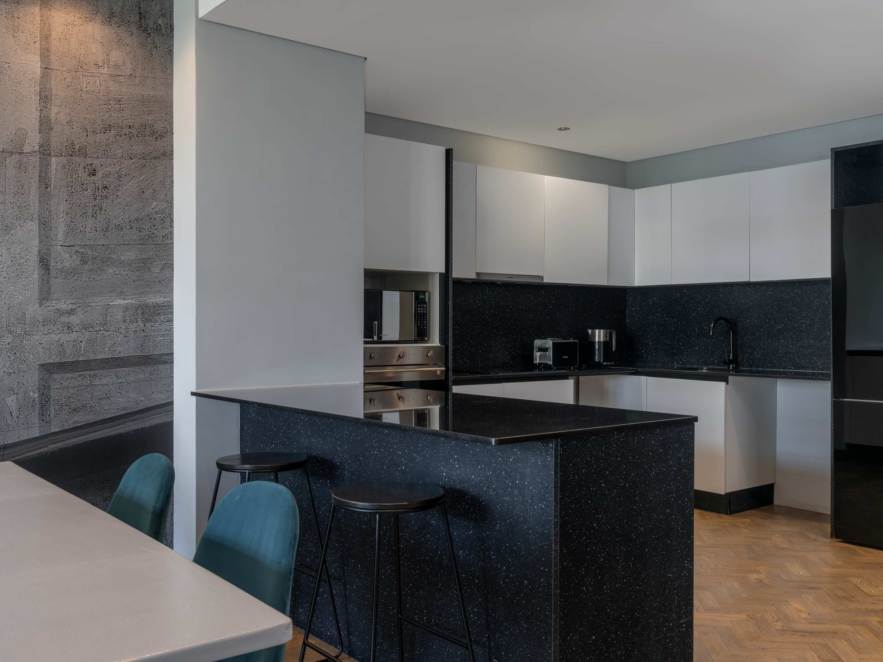 A modern kitchen with a central island, bar stools, and a dining area with a table and chairs.
