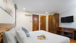 A hotel room with a bed, a flat-screen TV, wooden wardrobes, and a wall-mounted air conditioner. - Grand Sea View Hotel & Spa (Da Nang)