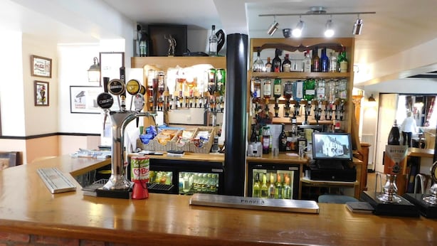 Un espace bar doté d’un comptoir en briques, de plusieurs robinets à bière et d’une variété de bouteilles d’alcool.
