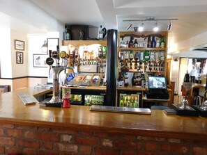 Zona de bar con mostrador de ladrillo, múltiples grifos de cerveza y una variedad de botellas de licor.