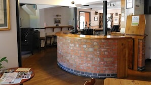 Un restaurant avec un comptoir en briques, des tables et des chaises en bois. Un panneau indiquant la sortie de secours est fixé au plafond.