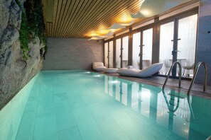 A swimming pool with clear water, wooden ceiling, and large windows. - Hotel B55 (Paris)