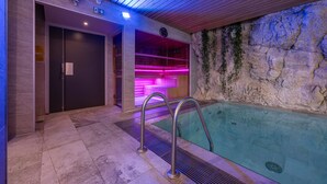 Ein moderner Poolbereich im Innenbereich mit Steinwand und Holzboden.