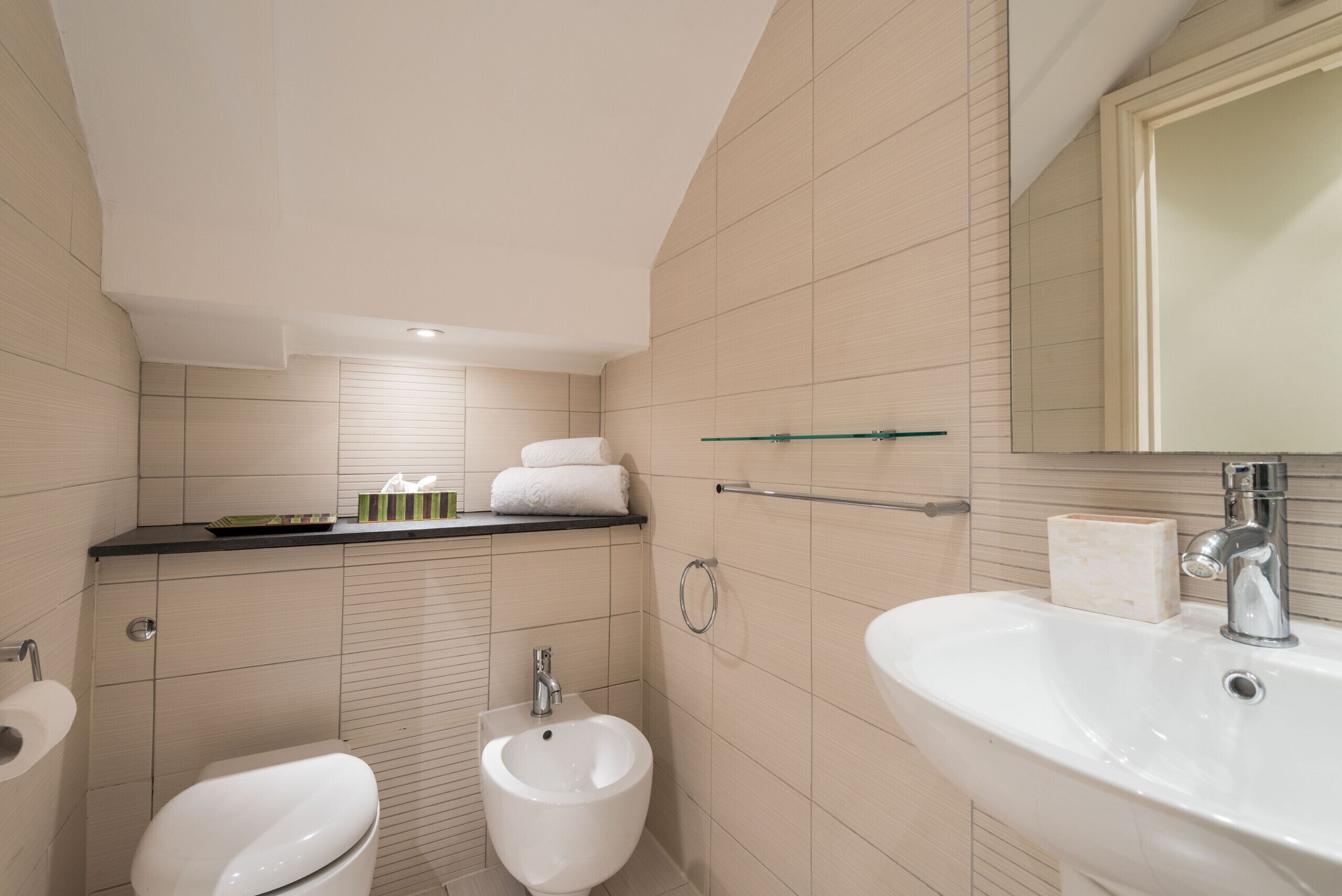 A modern bathroom with a bidet, a sink, and a mirror.