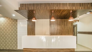 Een receptiebalie met een houten paneelontwerp, twee hanglampen en behang met een patroon aan de linker muur.