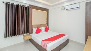 Een moderne hotelkamer met een groot bed, een plafondventilator, een airconditioning en een houten nachtkastje.