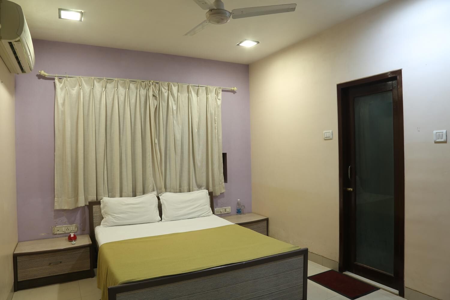 A bedroom with a bed, nightstands, a ceiling fan, and a door.