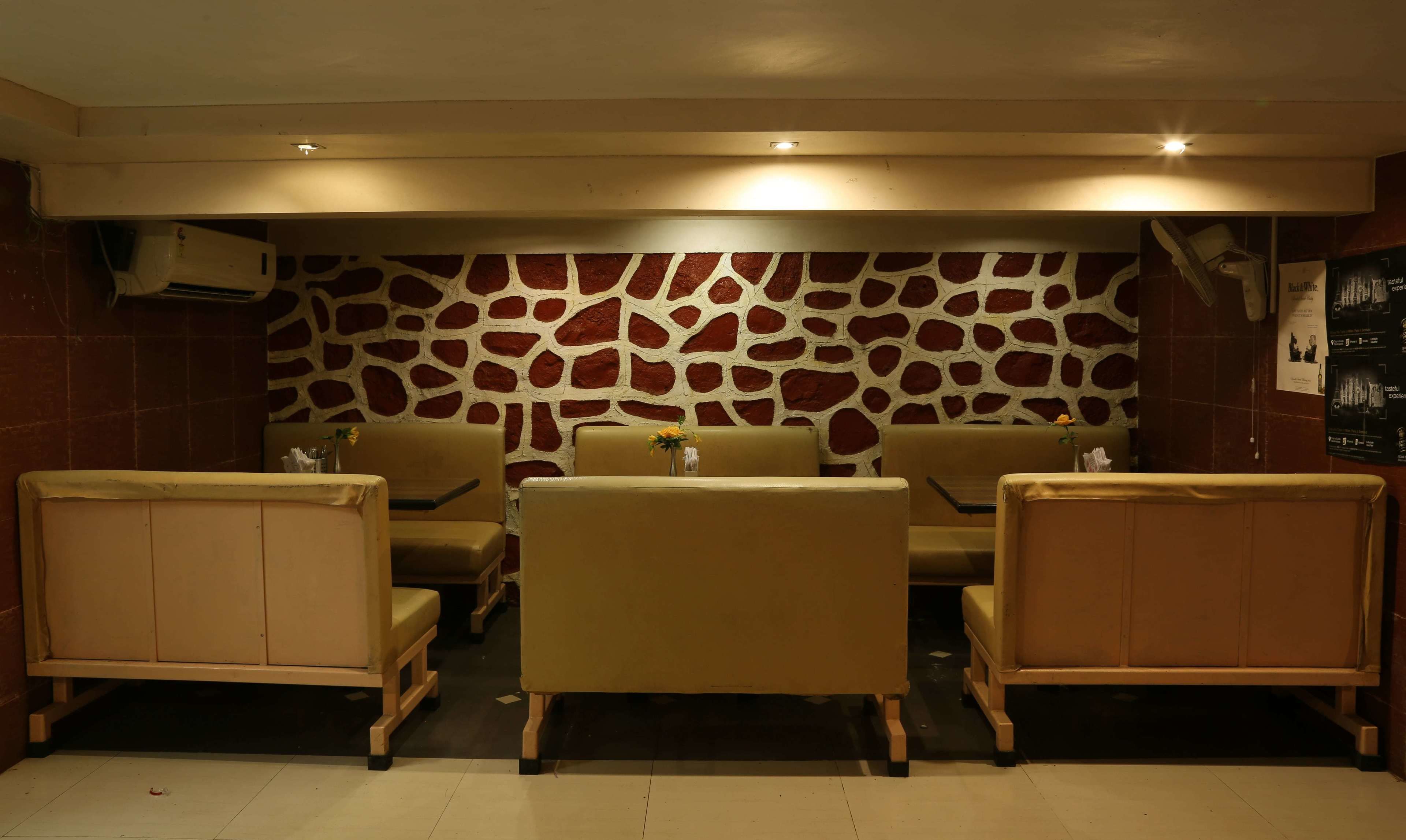 A restaurant with a stone wall, beige chairs, and a table.