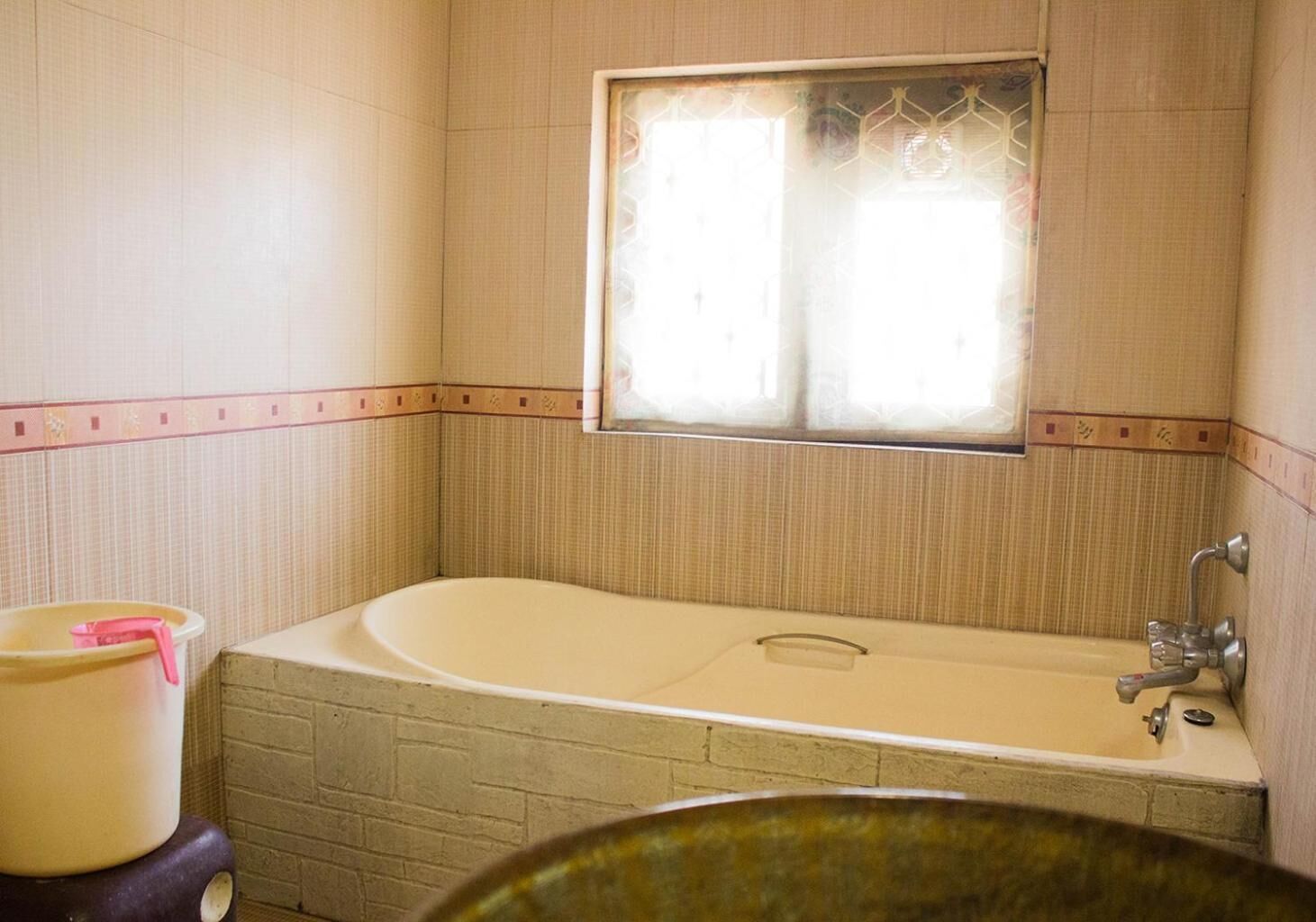 A bathroom with a bathtub, a window, and a toilet.