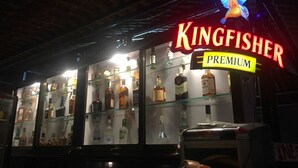Un bar Kingfisher Premium con un letrero de neón y una exhibici ón de distintas botellas de licor.