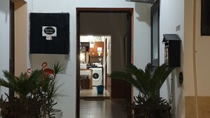 A hallway with two air conditioning units, a sign for 'Marina Rooms', and a view into a room with a washing machine. - Marina's Rooms (Larnaca)