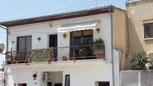 A two-story building with a balcony, potted plants, and a small entrance. - Marina's Rooms (Larnaca)