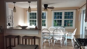 Une cuisine spacieuse avec un coin repas, de grandes fenêtres et un ventilateur de plafond.