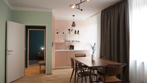 Cozinha moderna com mesa e cadeiras de madeira, luminária pendente e vista para a área de jantar adjacente.