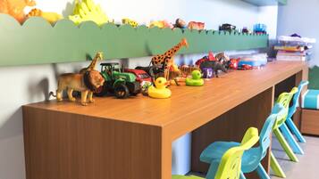 Un área de juegos infantiles con una larga mesa de madera que exhibe diversos vehículos y animales de juguete.