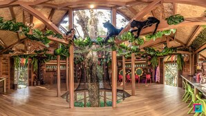 Un interior rústico con vigas de madera, una estructura arbórea central y diversas esculturas de animales.