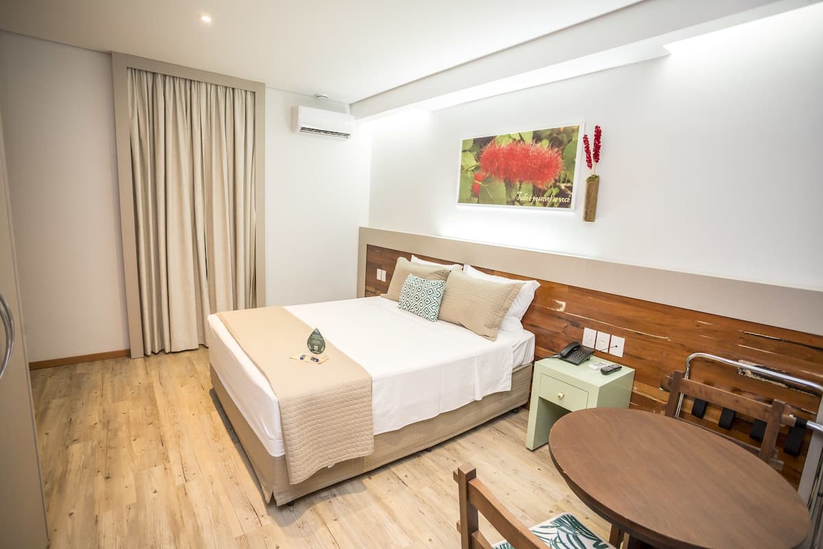 A hotel room with a bed, bedside table, chair, and a small table.