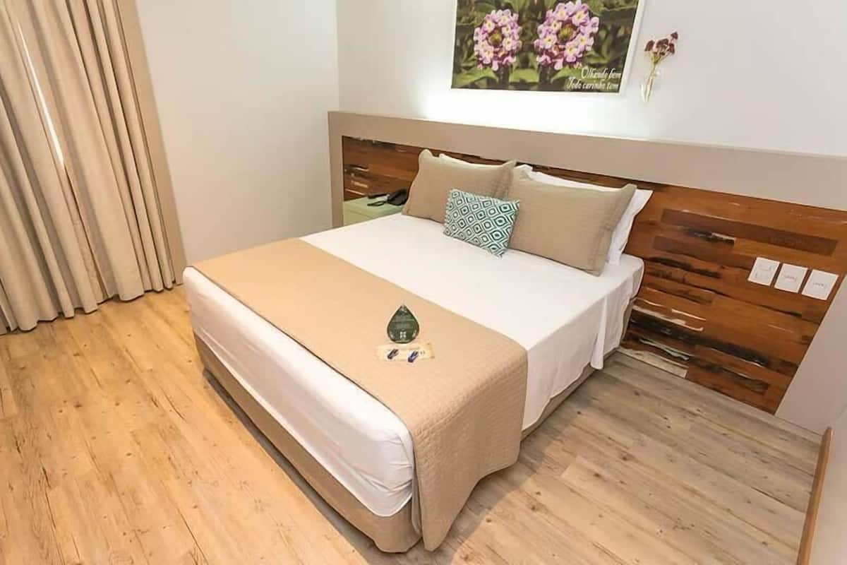 A bed with a wooden headboard, a beige bedspread, and a decorative stone.