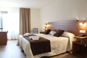 A hotel room with a large bed, two bedside tables, a nightstand, a chair, and a window with curtains. - Hotel Arzúa (Arzua)