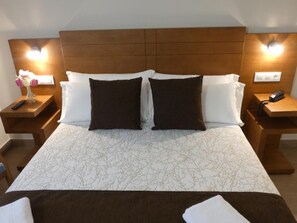 A hotel room with a large bed, two nightstands, a wooden headboard, and bedside lamps. - Hotel Arzúa (Arzua)
