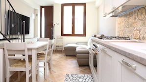 A compact kitchen with a dining area, a sofa, and a small table. - Terrazza della Rocca (Cefalù)