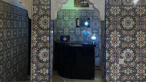A room with intricate tile work, a chandelier, and a small table with a lamp. - Dar Dikrayat (Marrakech)