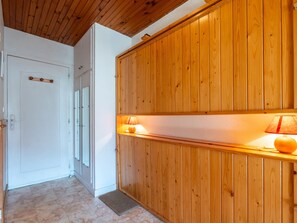 Un couloir aux murs lambrissés, une porte blanche et une petite table sur laquelle se trouve une lampe.