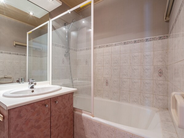Une salle de bain équipée d’un lavabo, d’un miroir, d’une douche et d’une baignoire.