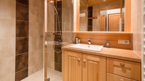 A modern bathroom with a glass-enclosed shower, wooden cabinetry, and a large mirror. - Renovated 3* studio in La Clusaz with south terrace (La Clusaz)