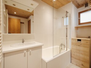 A modern bathroom with a white sink, a glass-enclosed shower, and wooden cabinetry. - Bright apartment, near slopes, pets allowed (La Clusaz)