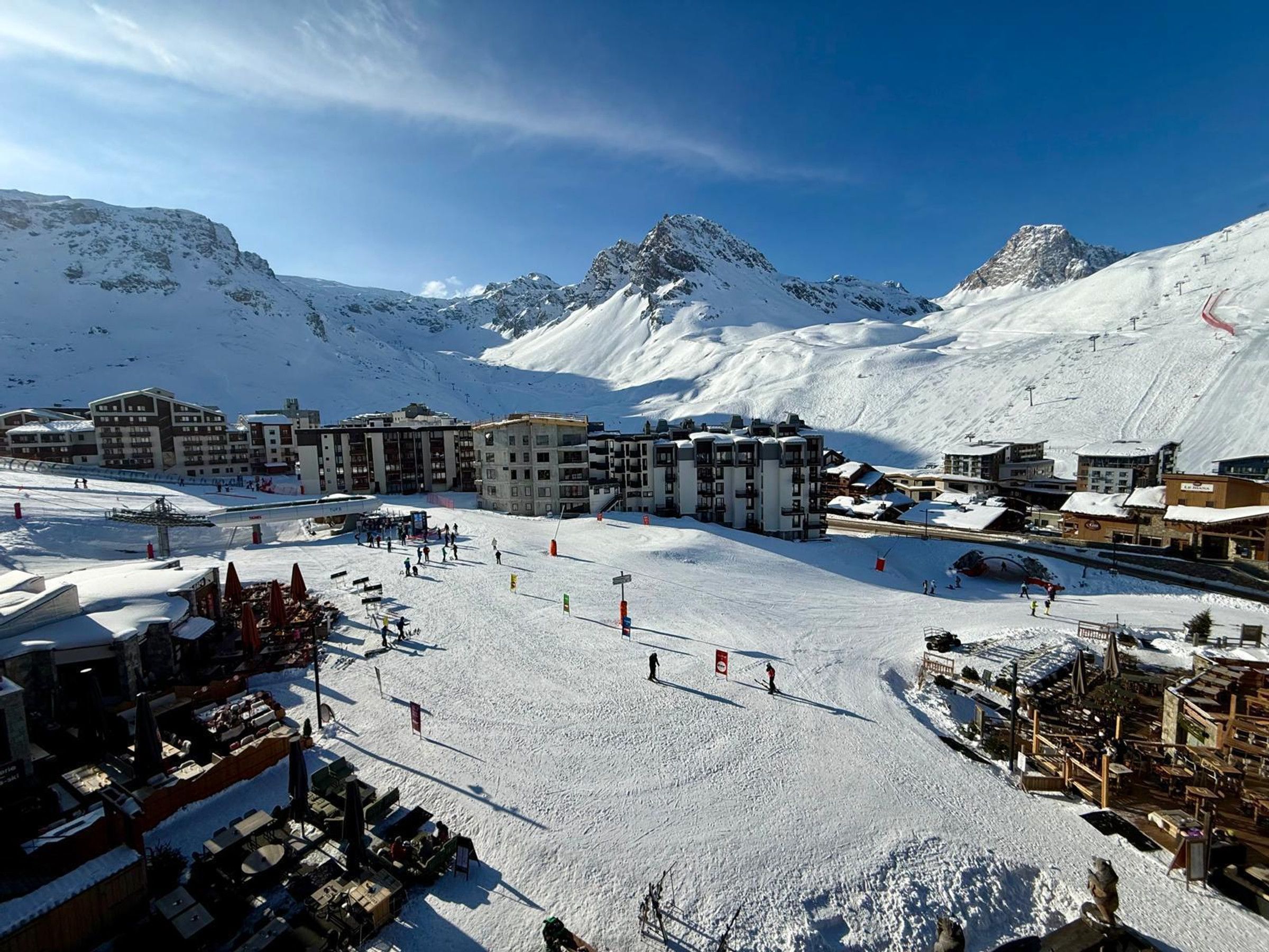 Een skiparadijs bedekt met sneeuw, met meerdere gebouwen, waaronder hotels en restaurants, en een piste.