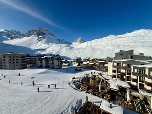 A snow-covered mountain town with buildings, a ski slope, and a clear sky.