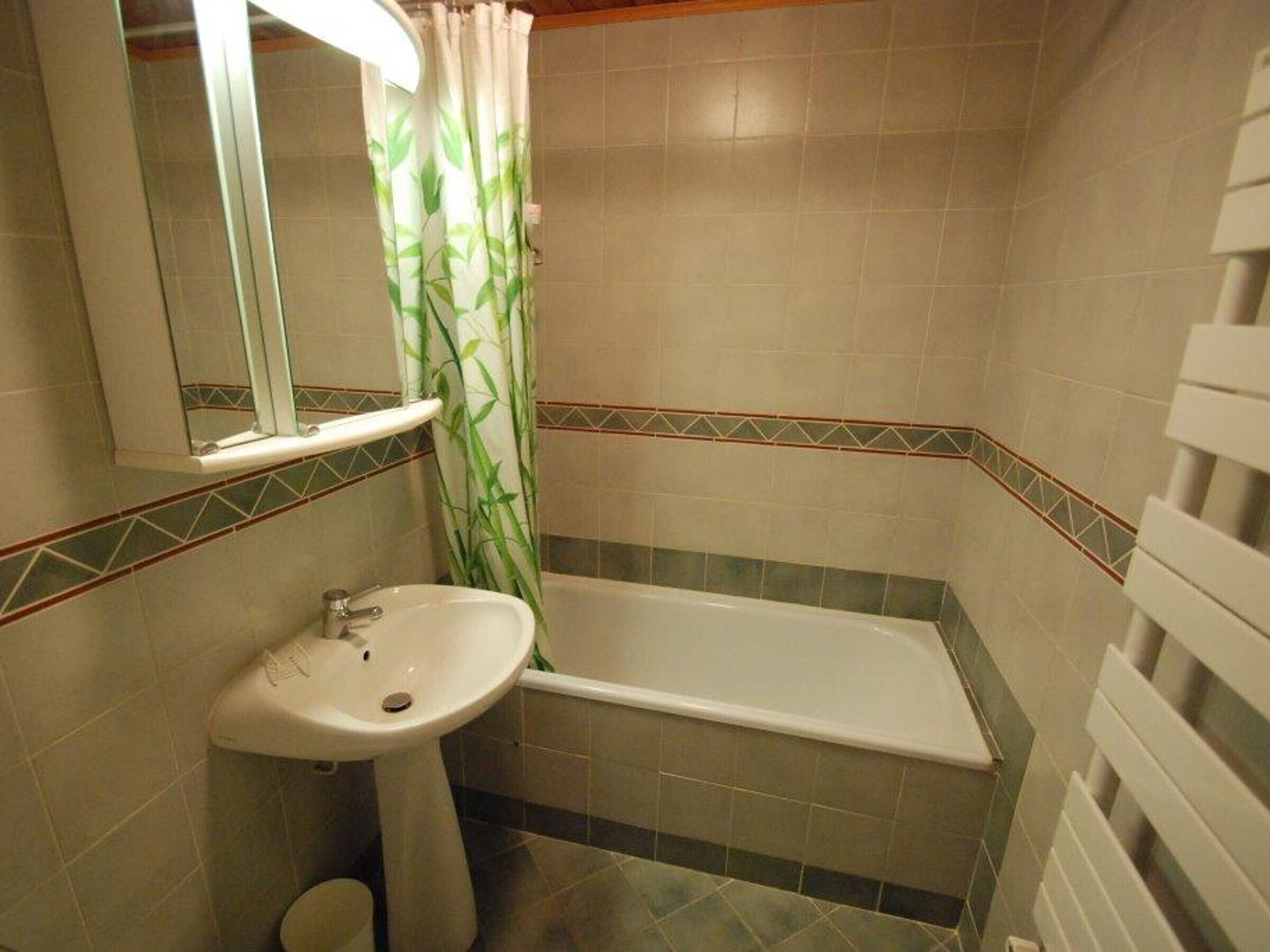 Een badkamer met een wastafel, spiegel en bad.
