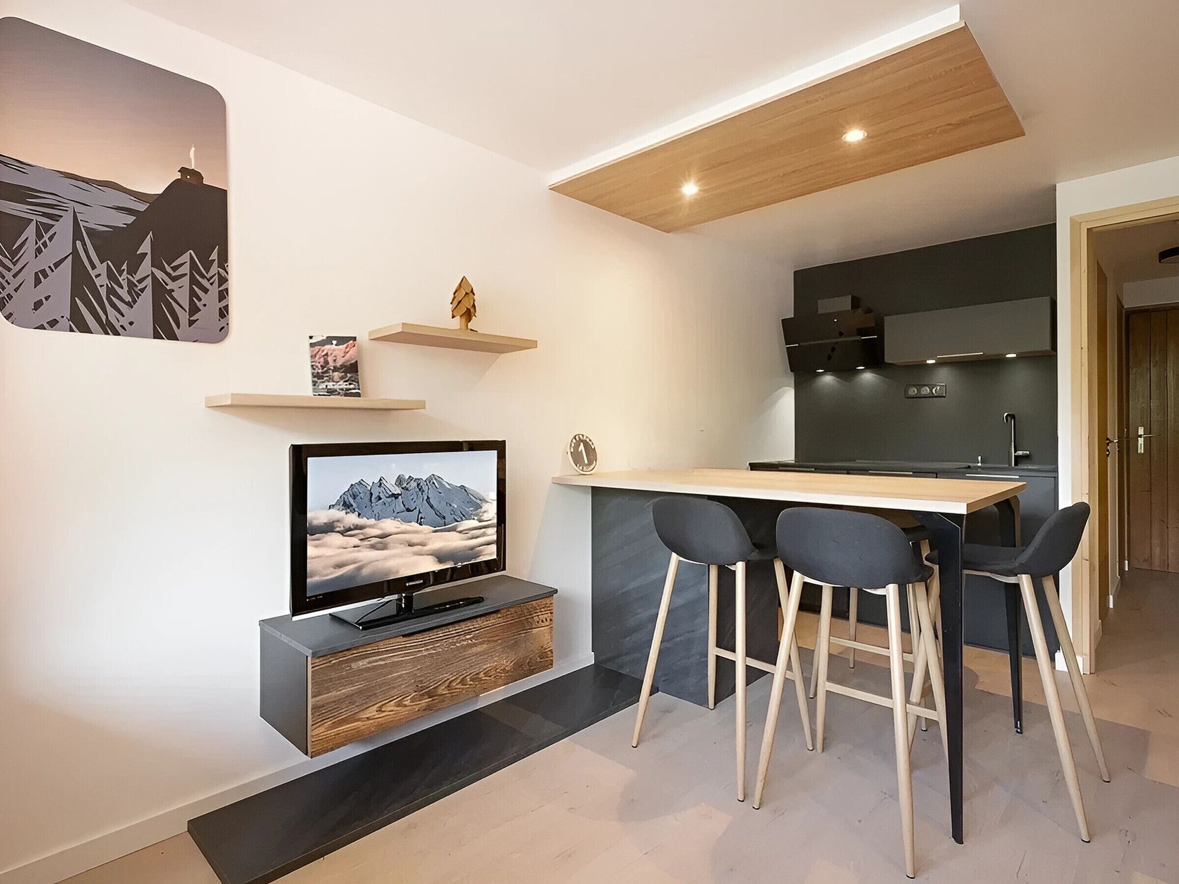 Une cuisine moderne avec un plafond en bois, un téléviseur encastré et un coin bar avec des tabourets.