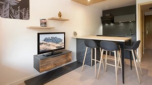 Eine moderne Küche mit Holzboden, einem eingebauten Fernseher und einer Bar mit Hockern.